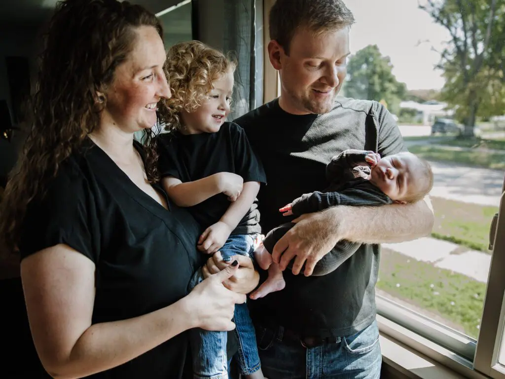 Kate and Her Family, Husband and two kids, in a candid portrait looking out a window